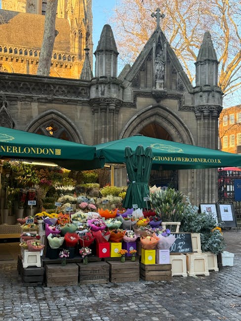 An outdoor flower stall situated in front of a historic stone church with pointed arch windows and ornate Gothic architectural details. The stall features a variety of fresh floral bouquets and arrang